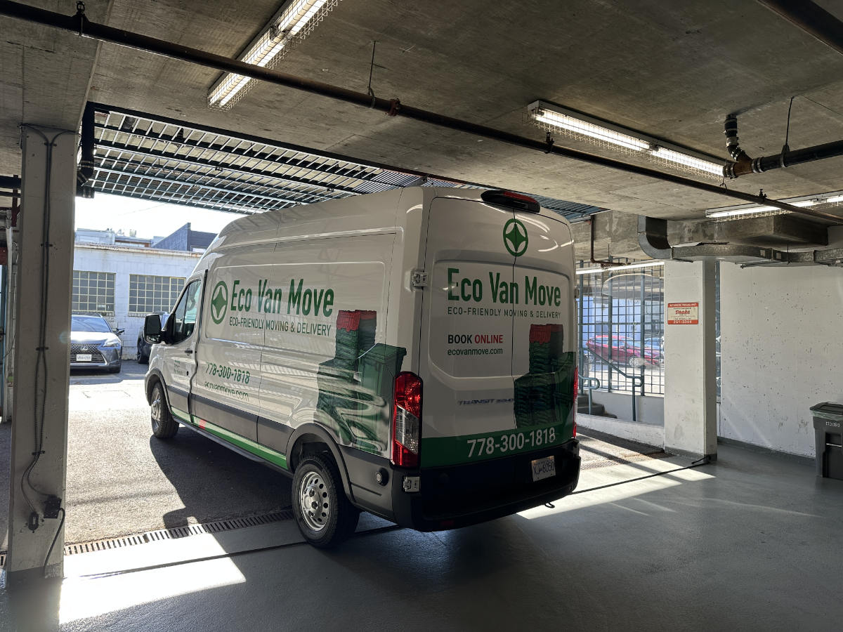 White Ford Transit van with Eco Van Move branding parked in an outdoor lot on a sunny day in Vancouver.