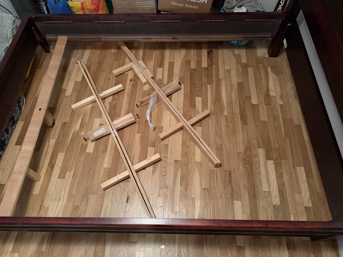 Eco Van Move assembling a wooden bed frame as part of a residential moving and furniture setup service.