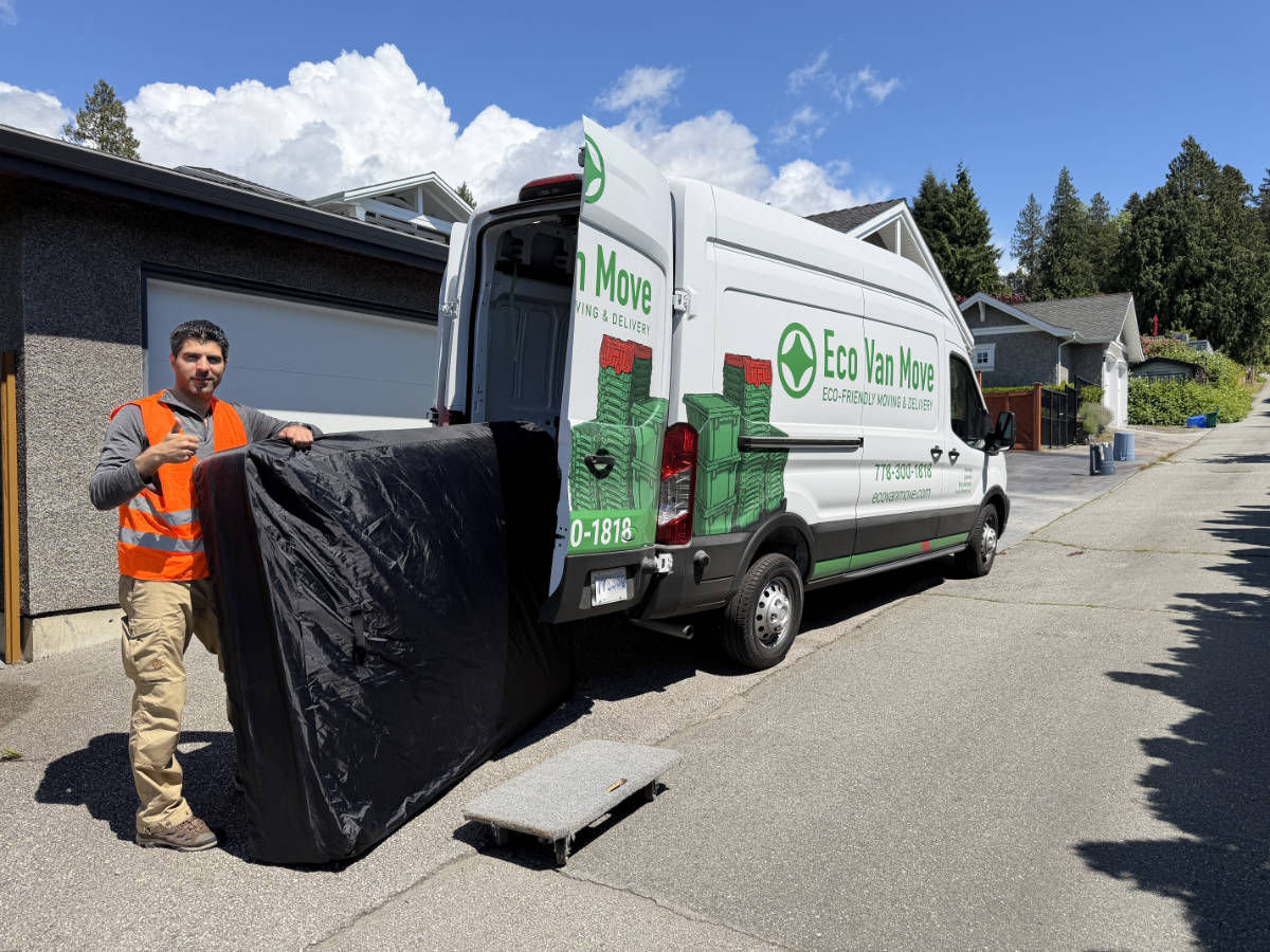 Eco Van Move staff loading a protected mattress into a cargo van for delivery in Metro Vancouver.