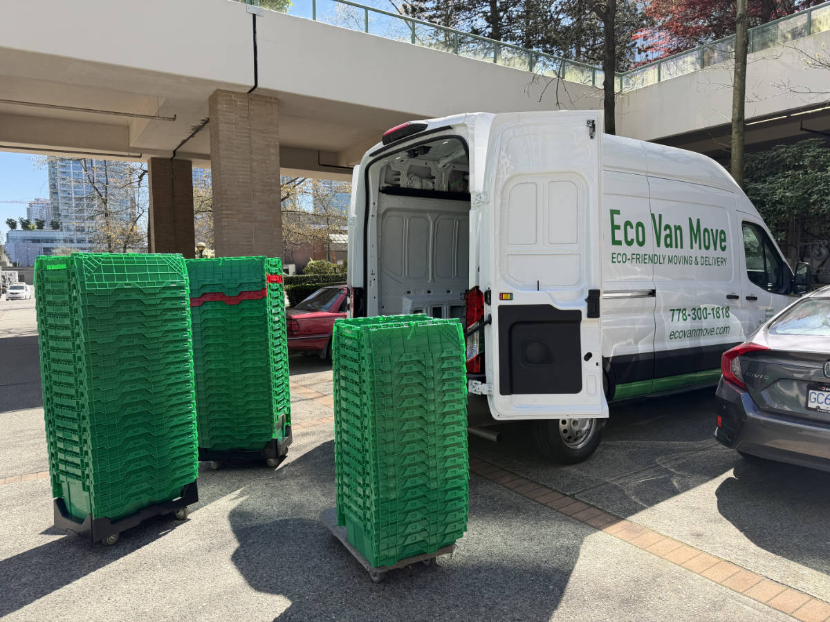 White Eco Van Move van with open doors parked next to three tall stacks of green reusable moving boxes.