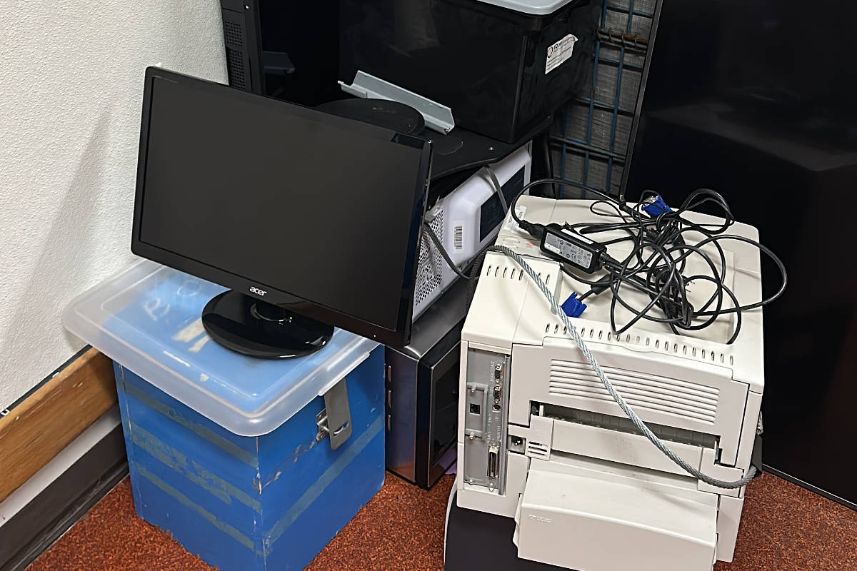 Old computer monitor, printer, and tangled cables stacked together for office e-waste removal.